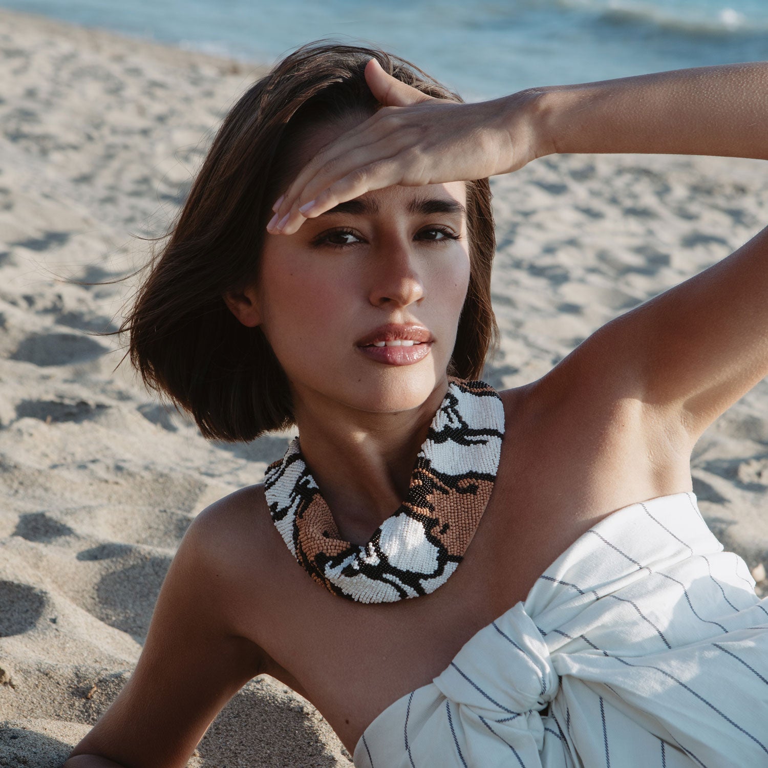 mini scarf necklace with brown and black beads on a woman at the beach