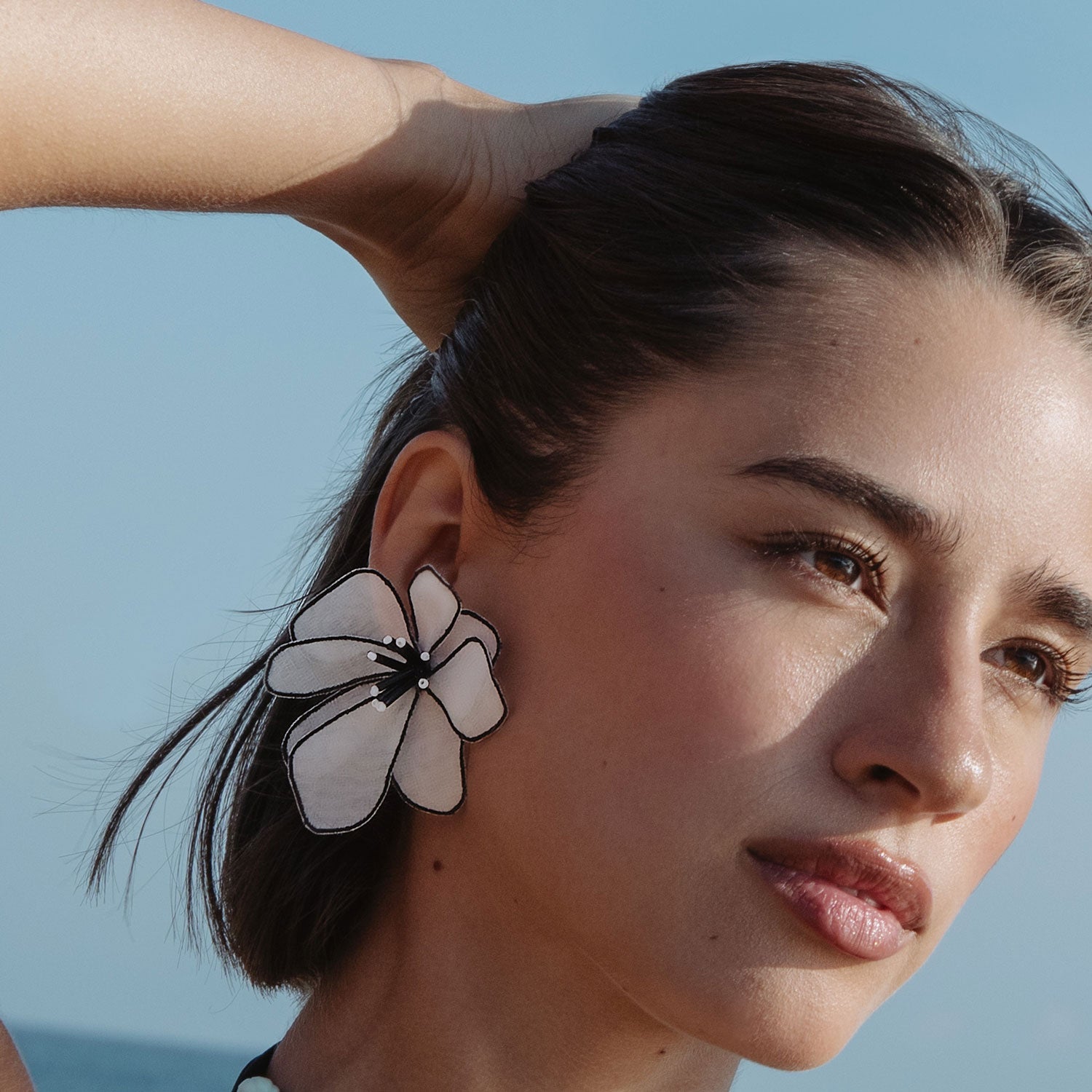 woman with short dark hair wearing a floral statement earring