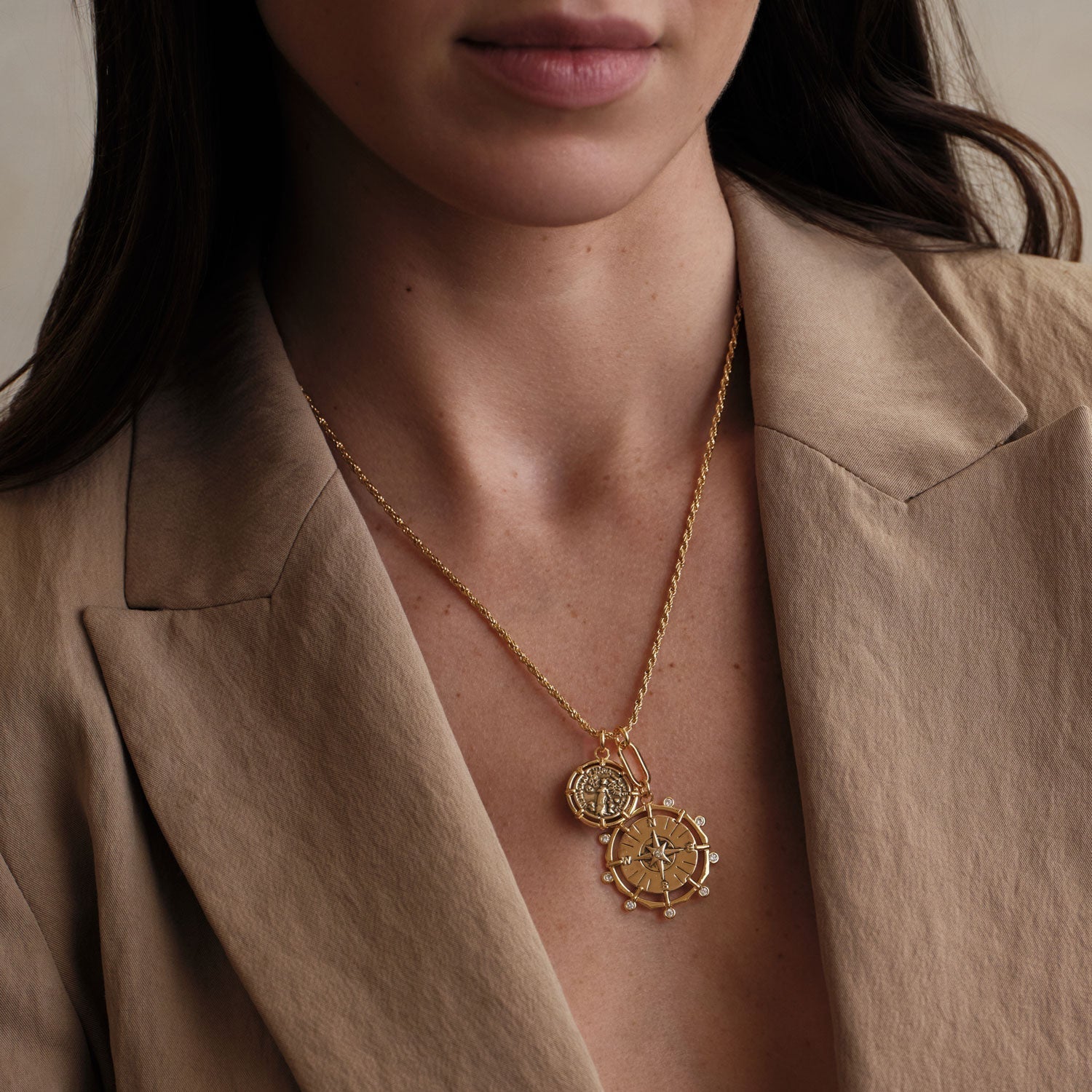 gold two pendant necklace and a brown earth toned light blazer being worn by a woman