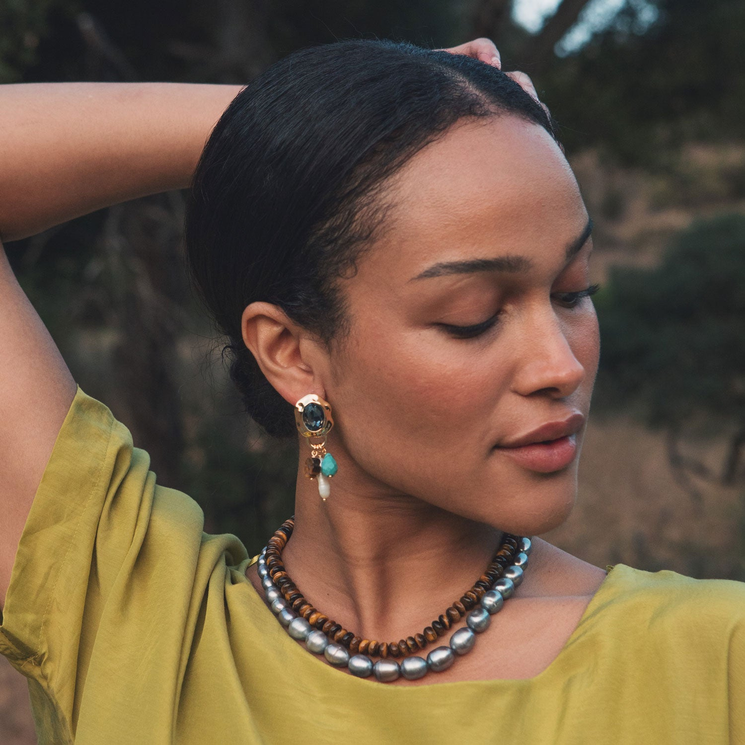 Model wearing beaded necklaces around neck and colorful drop earring