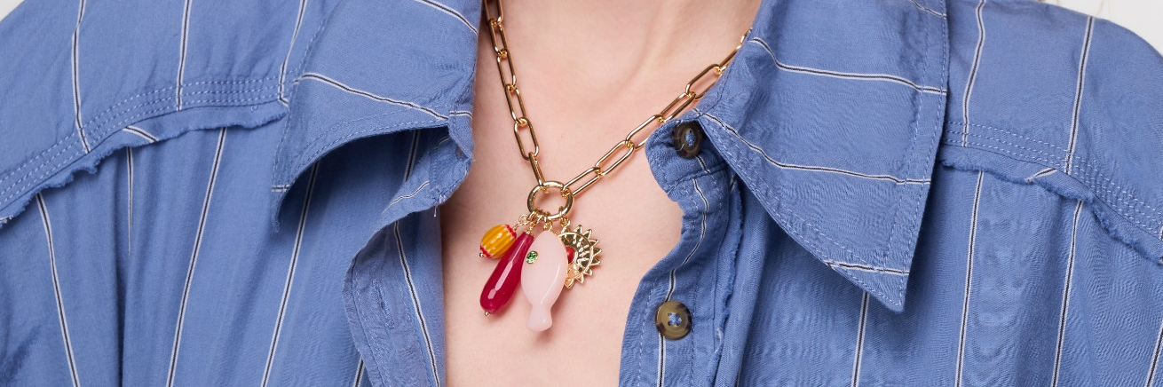 Model wearing chain necklace with colorful charms in blue blouse