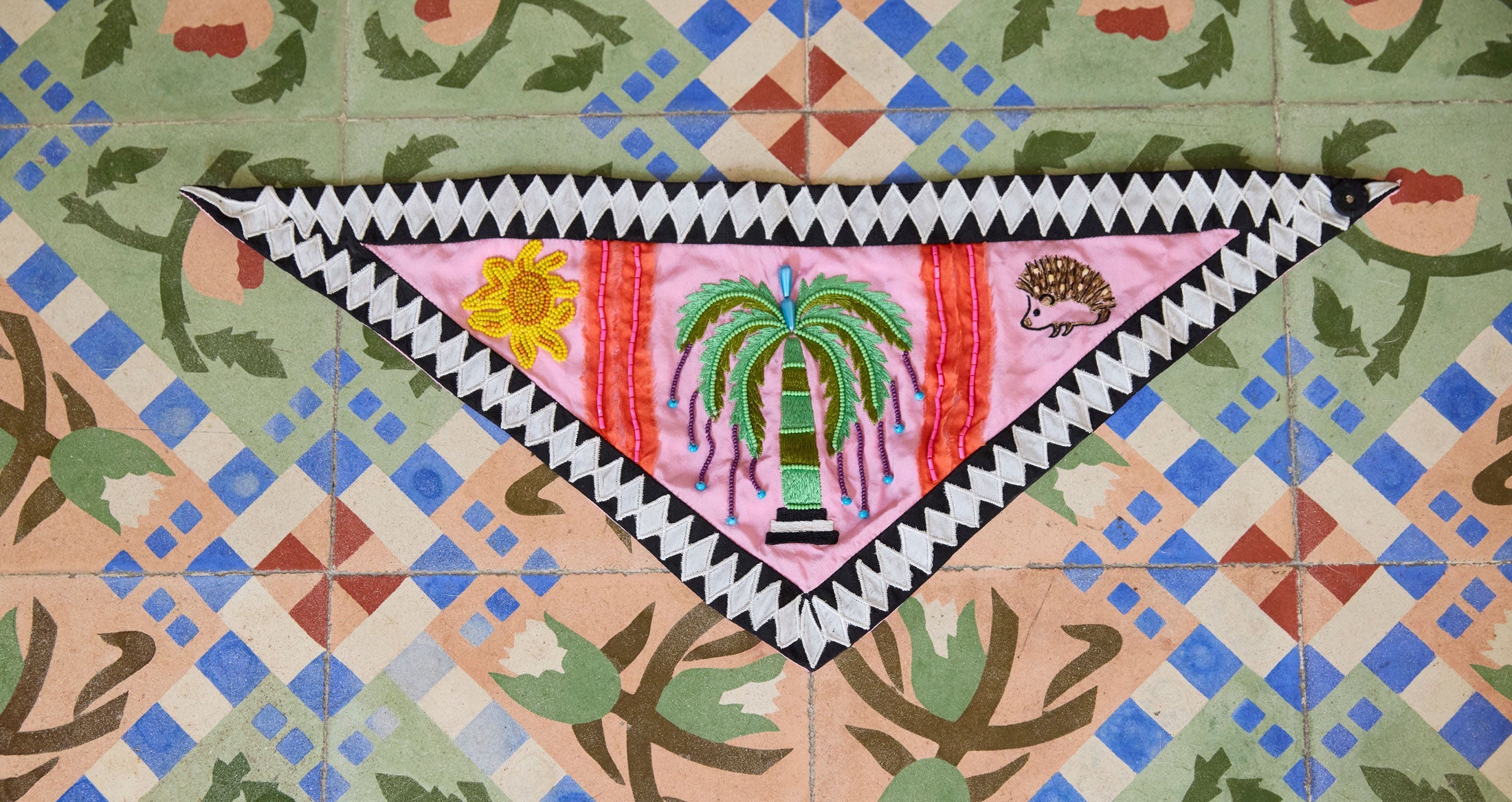 Woman wearing colorful top and large beaded earrings.