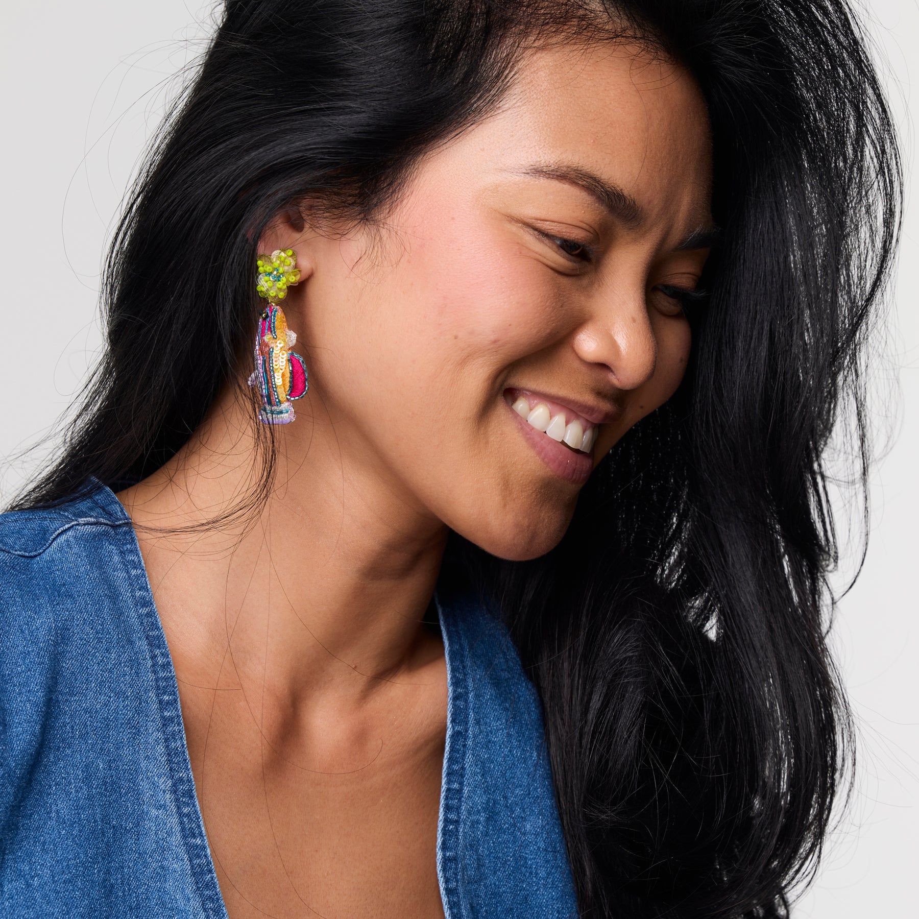 Woman wearing colorful earrings with a neutral background