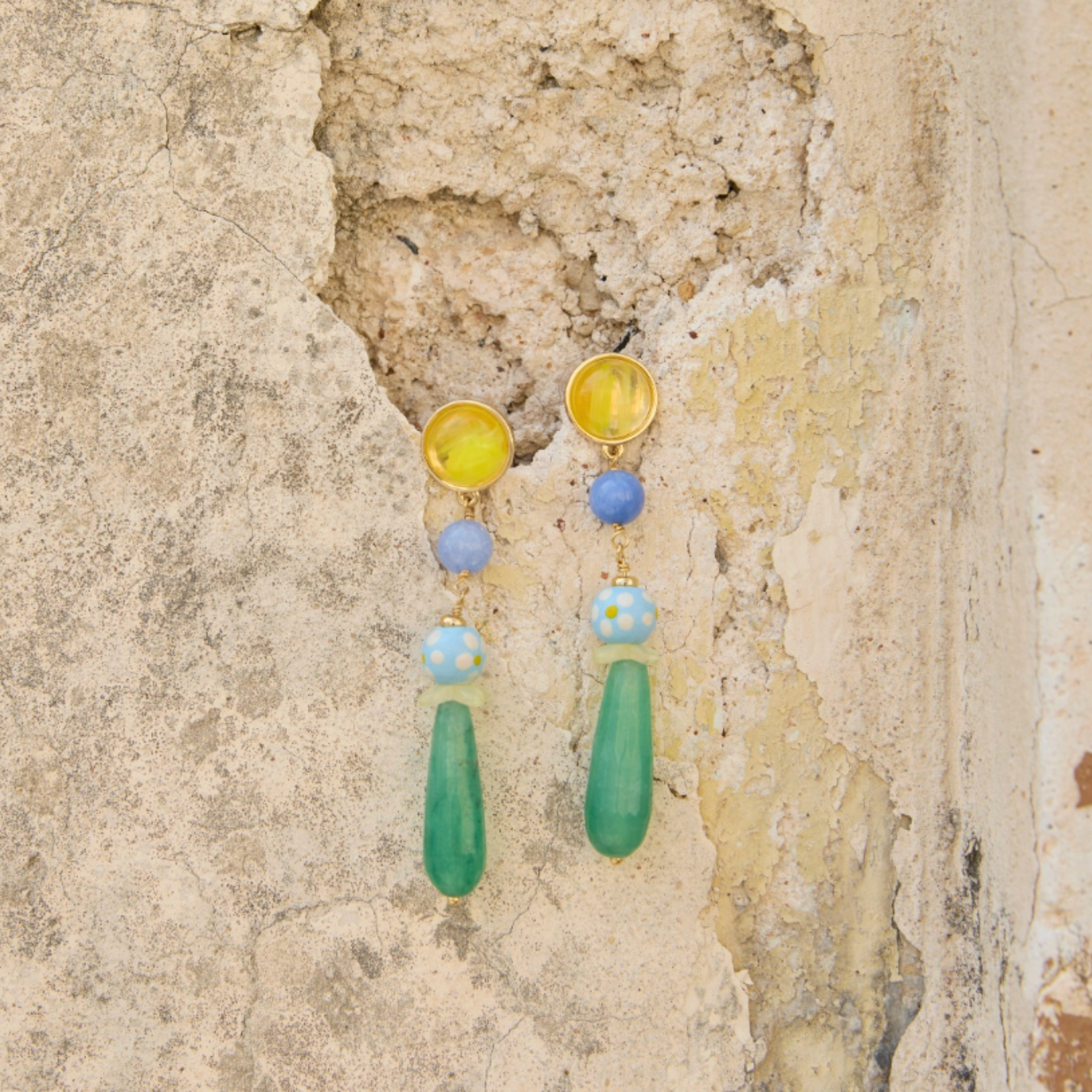 Colorful drop earrings against stone wall background