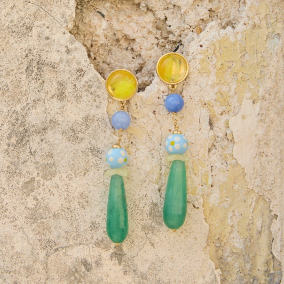 Colorful drop earrings against stone wall background