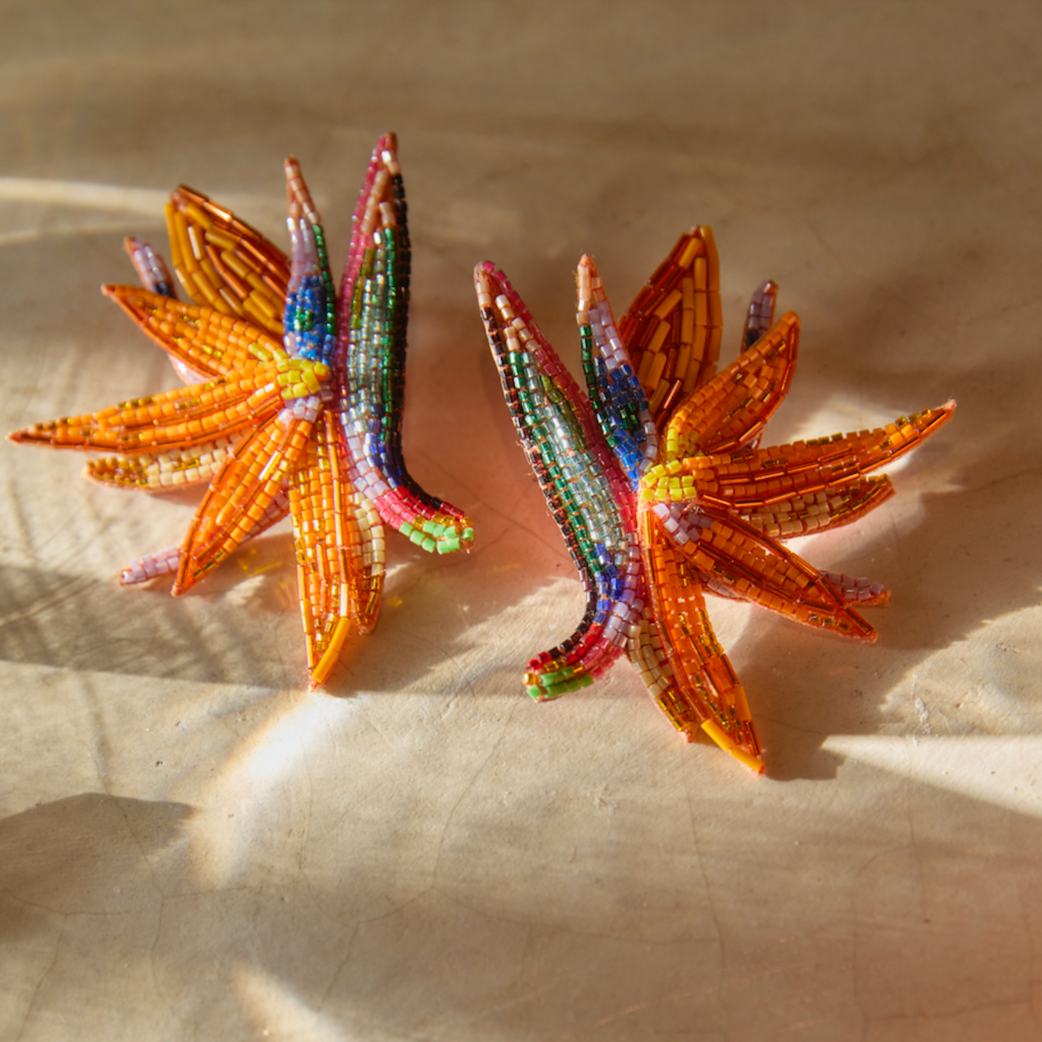 Pair of beaded flower earrings on a textured surface