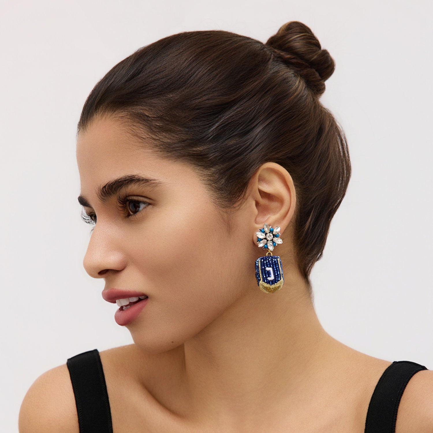 Beaded dreidel drop earrings styled on model in black top with white background