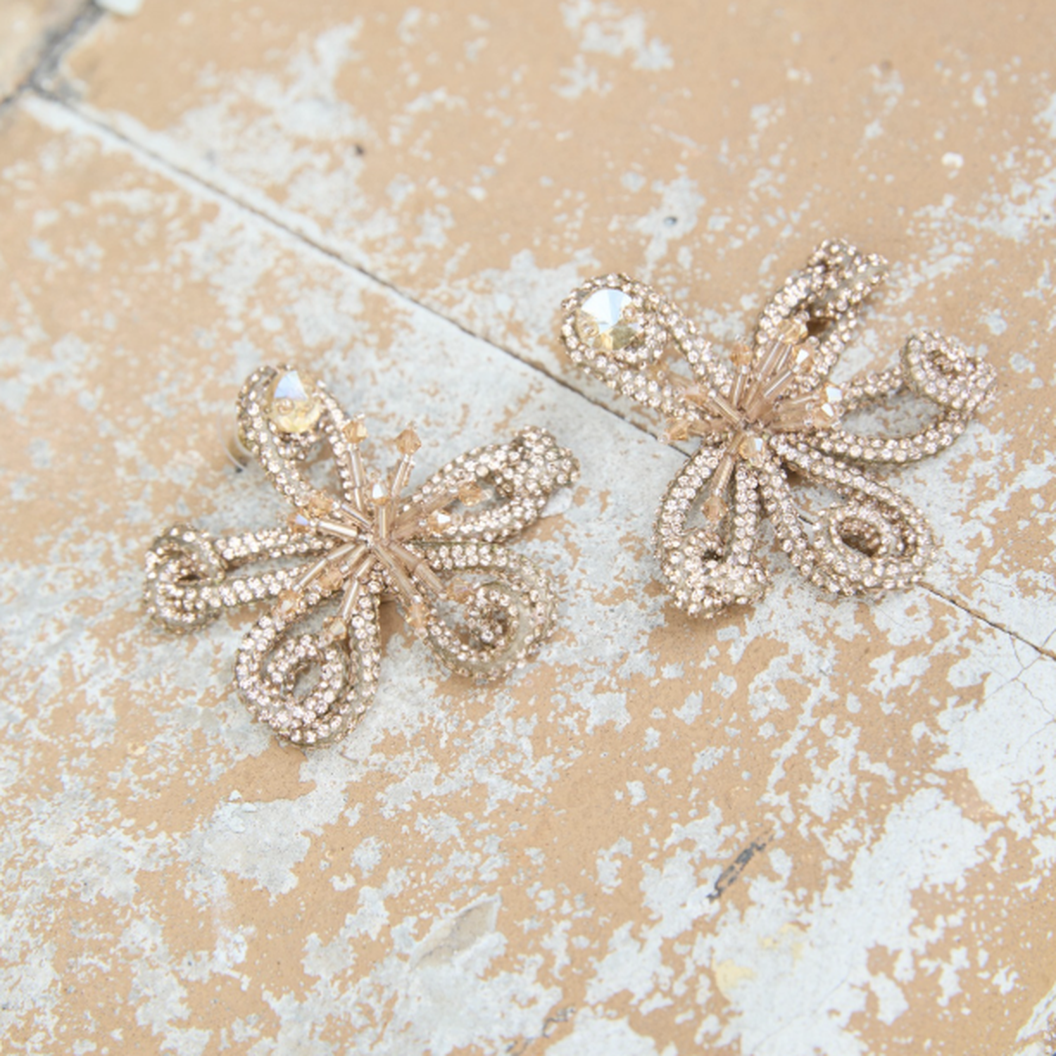 Gold beaded and embroidered earrings on stone background