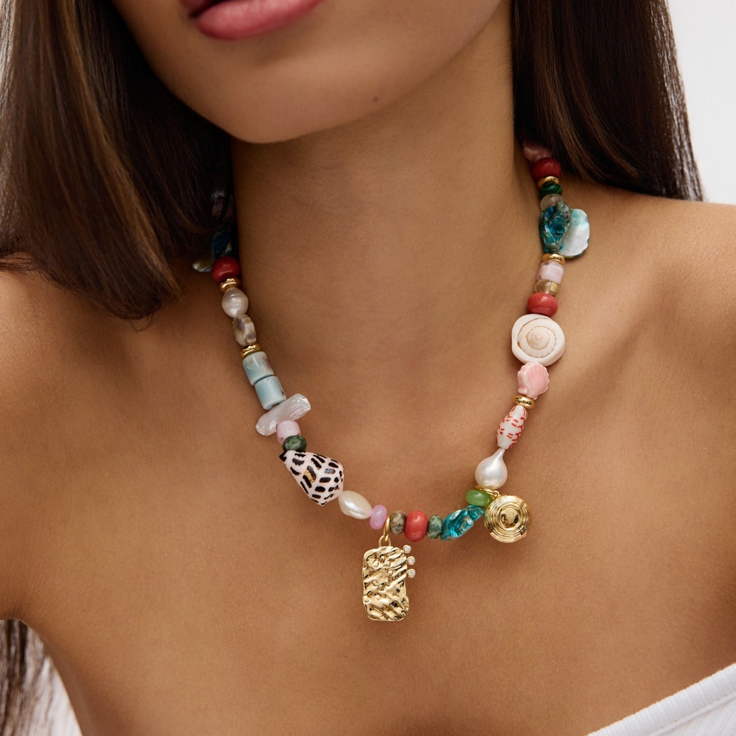 Colorful beaded necklace with a gold charm worn by a person