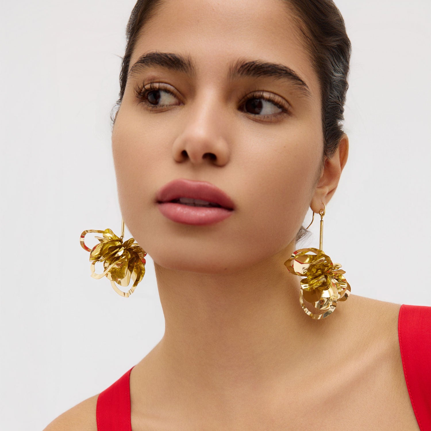 Woman wearing gold earrings with a plain background