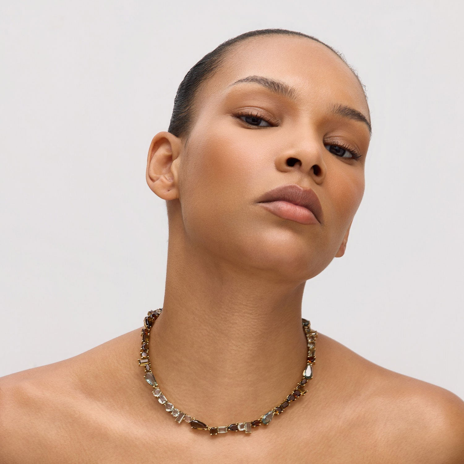 Woman wearing a crystal necklace against a plain background