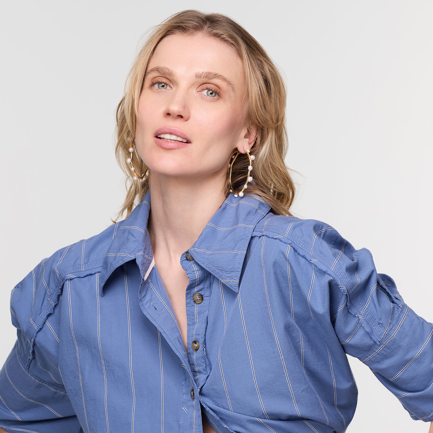 Woman wearing a blue pinstripe shirt against a plain background