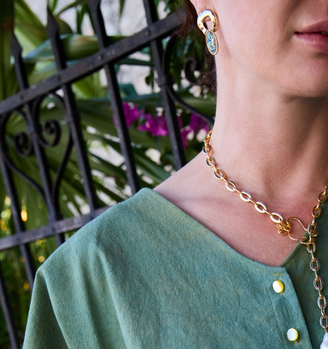 Person wearing a gold chain necklace with a blurred background