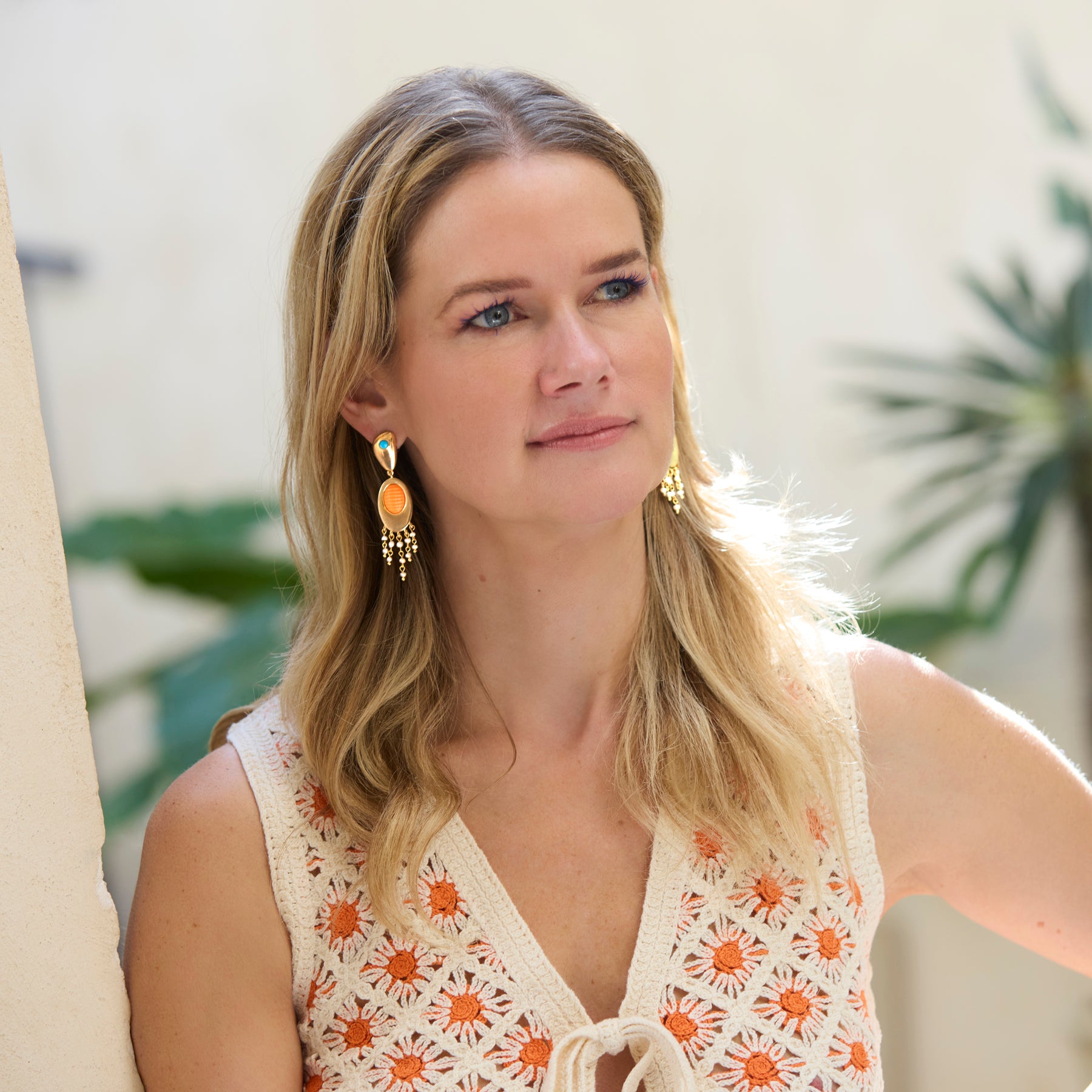 Model wearing gold drop earrings with white and orange crochet dress