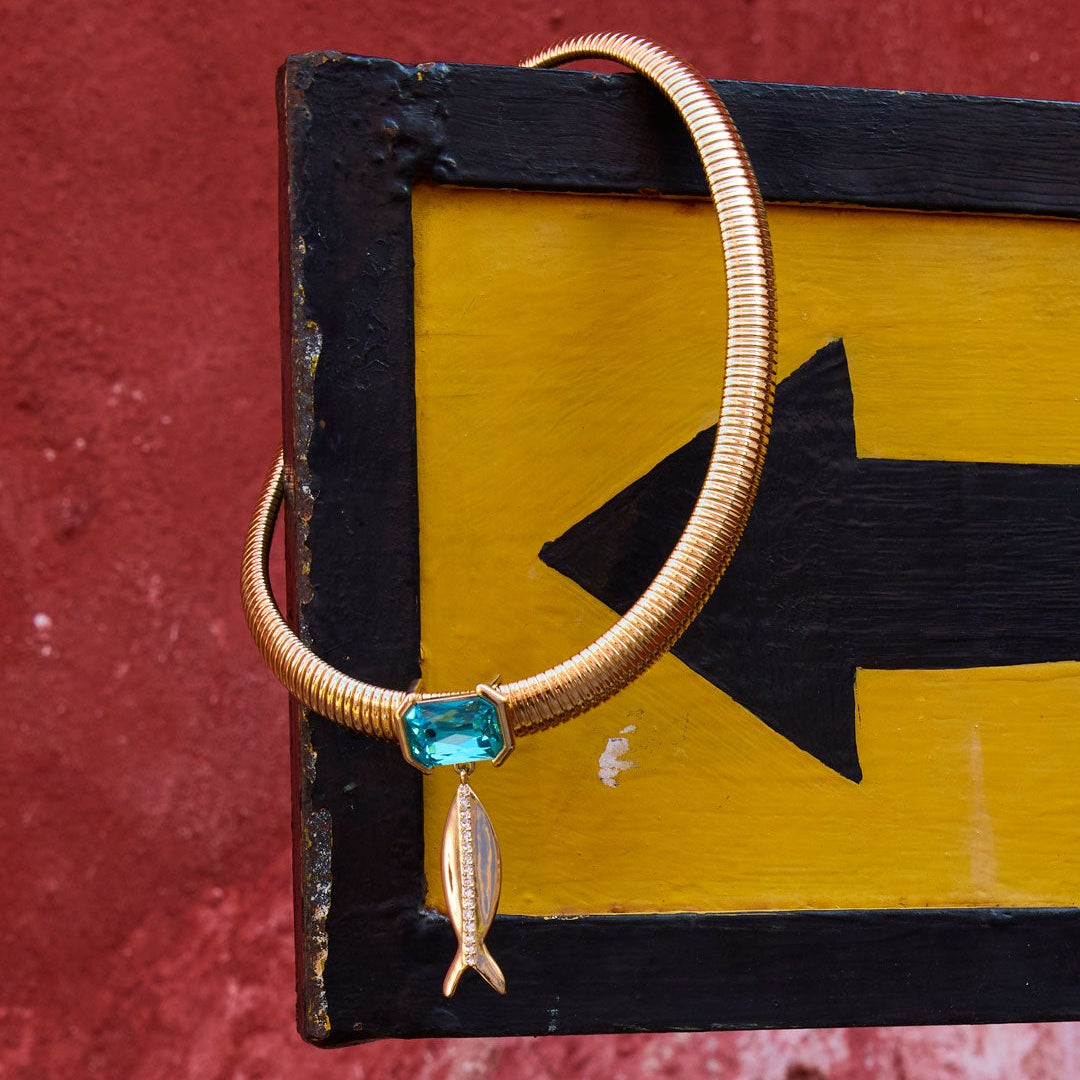 Necklace with a blue gemstone on a yellow and black sign against a red wall.