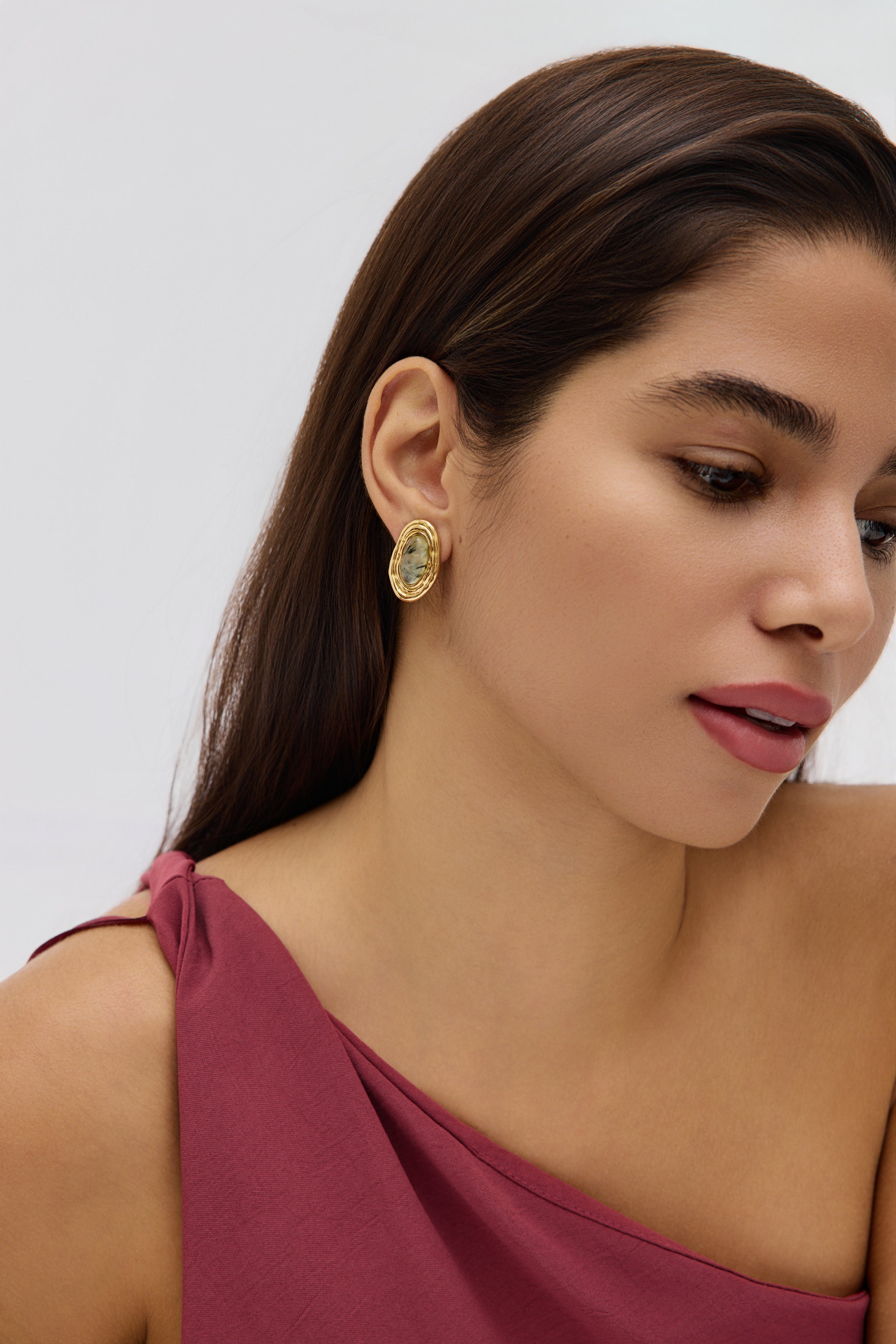 Woman wearing gold earrings with a plain background