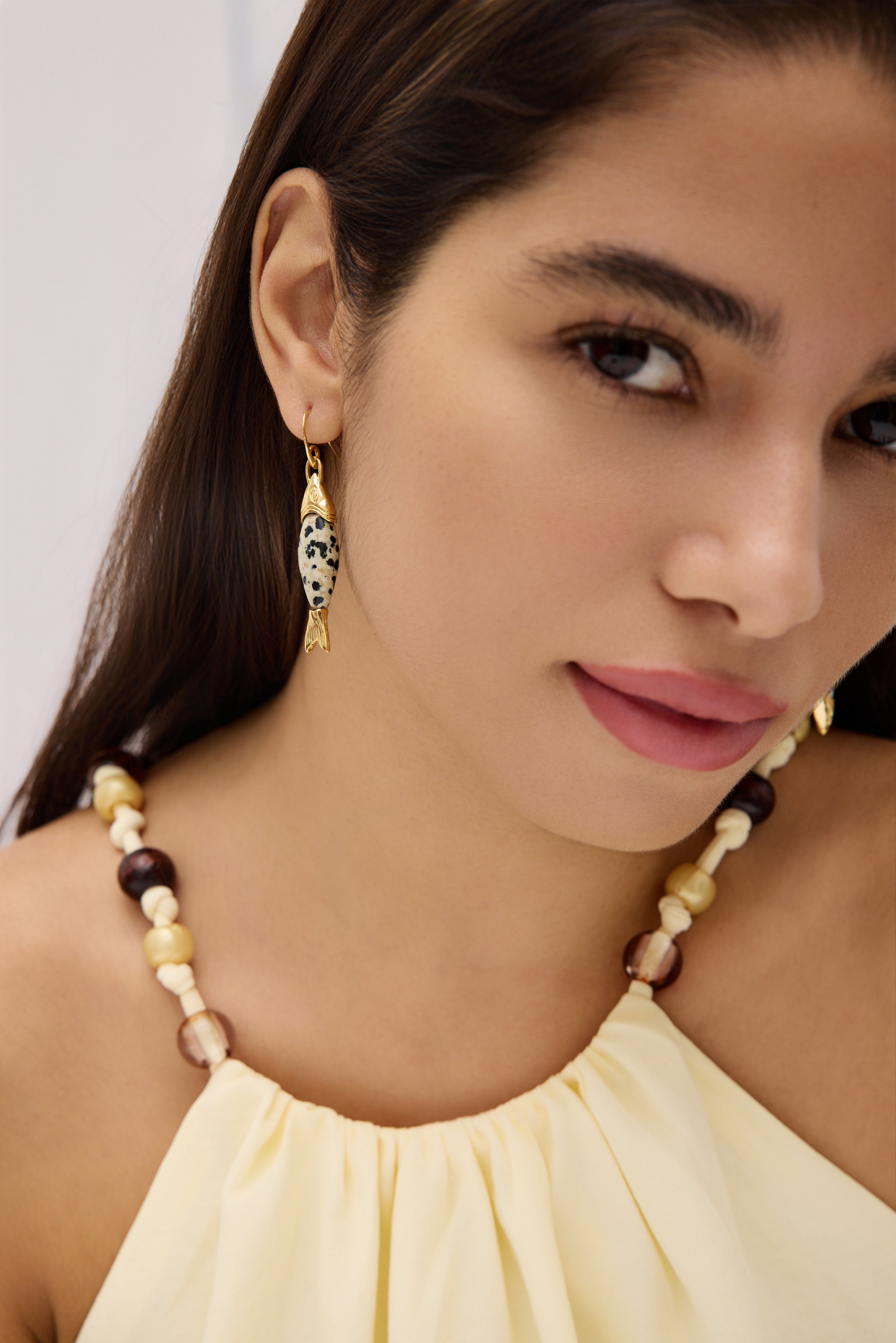Woman wearing a beaded necklace and earrings with a neutral background