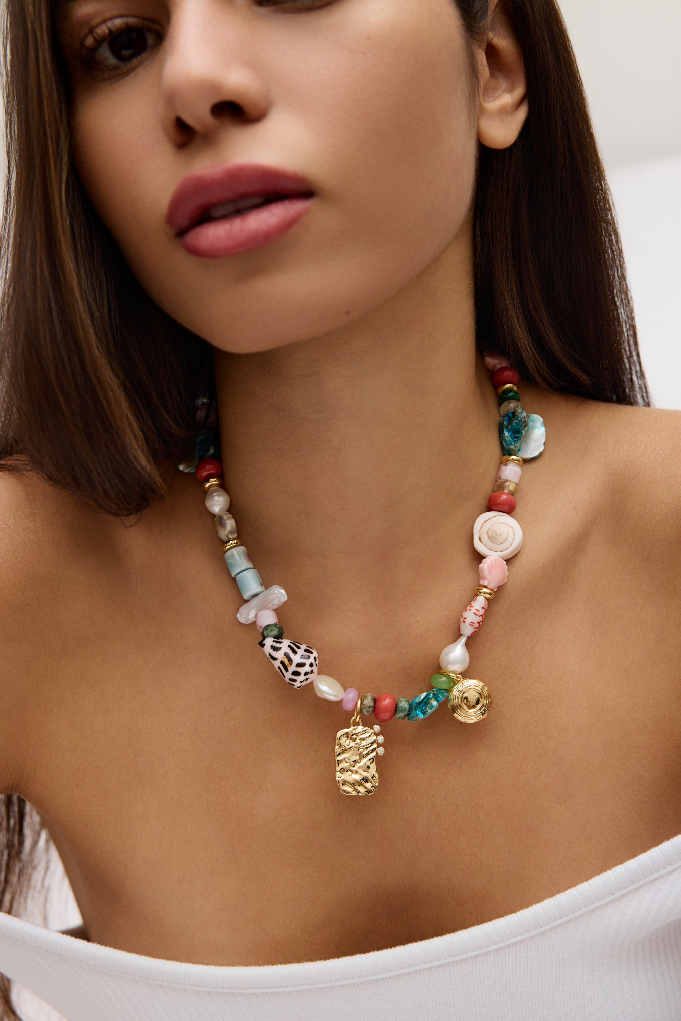 Close-up of a woman wearing a colorful beaded necklace with a white top.