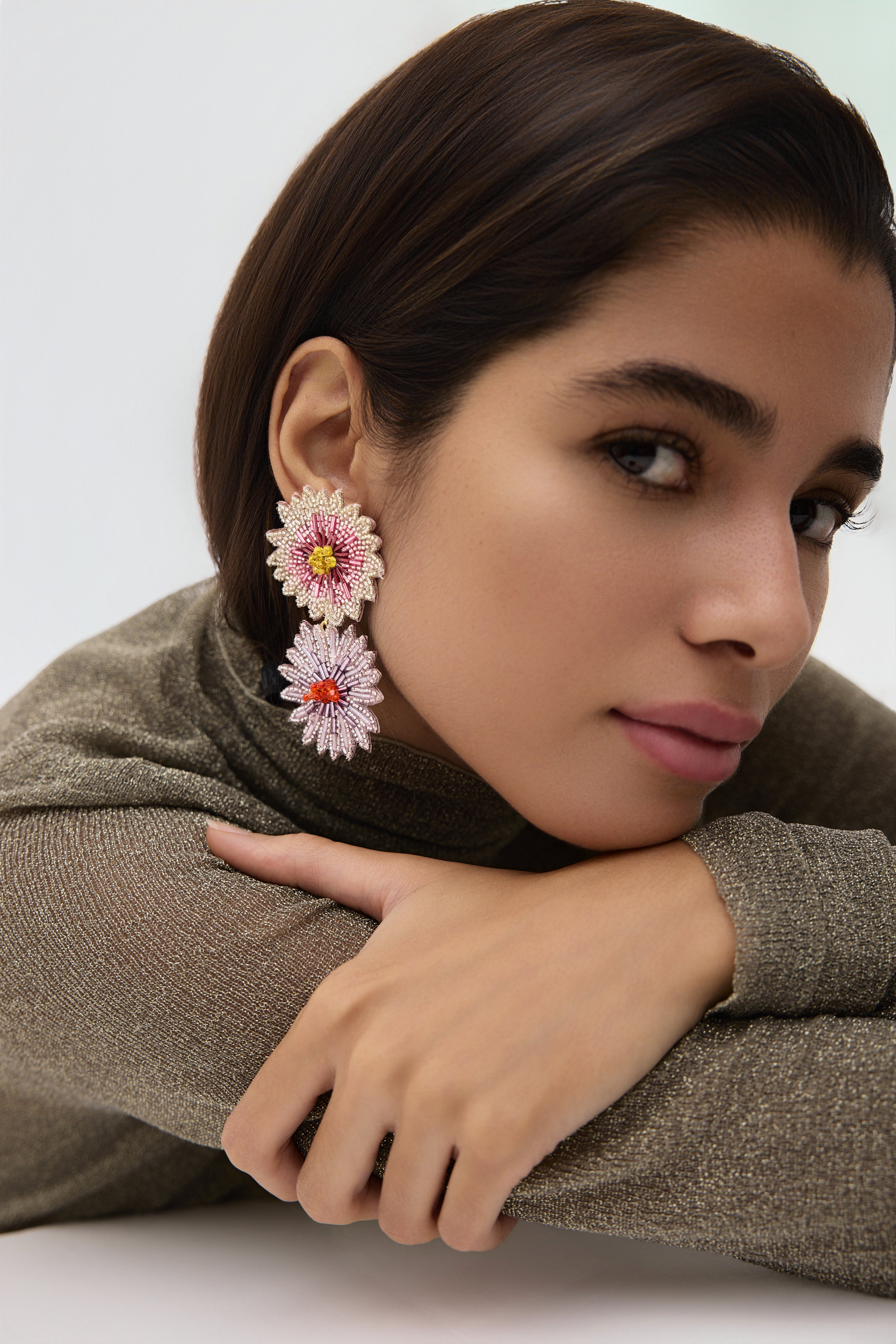 Woman wearing floral earrings with a neutral background