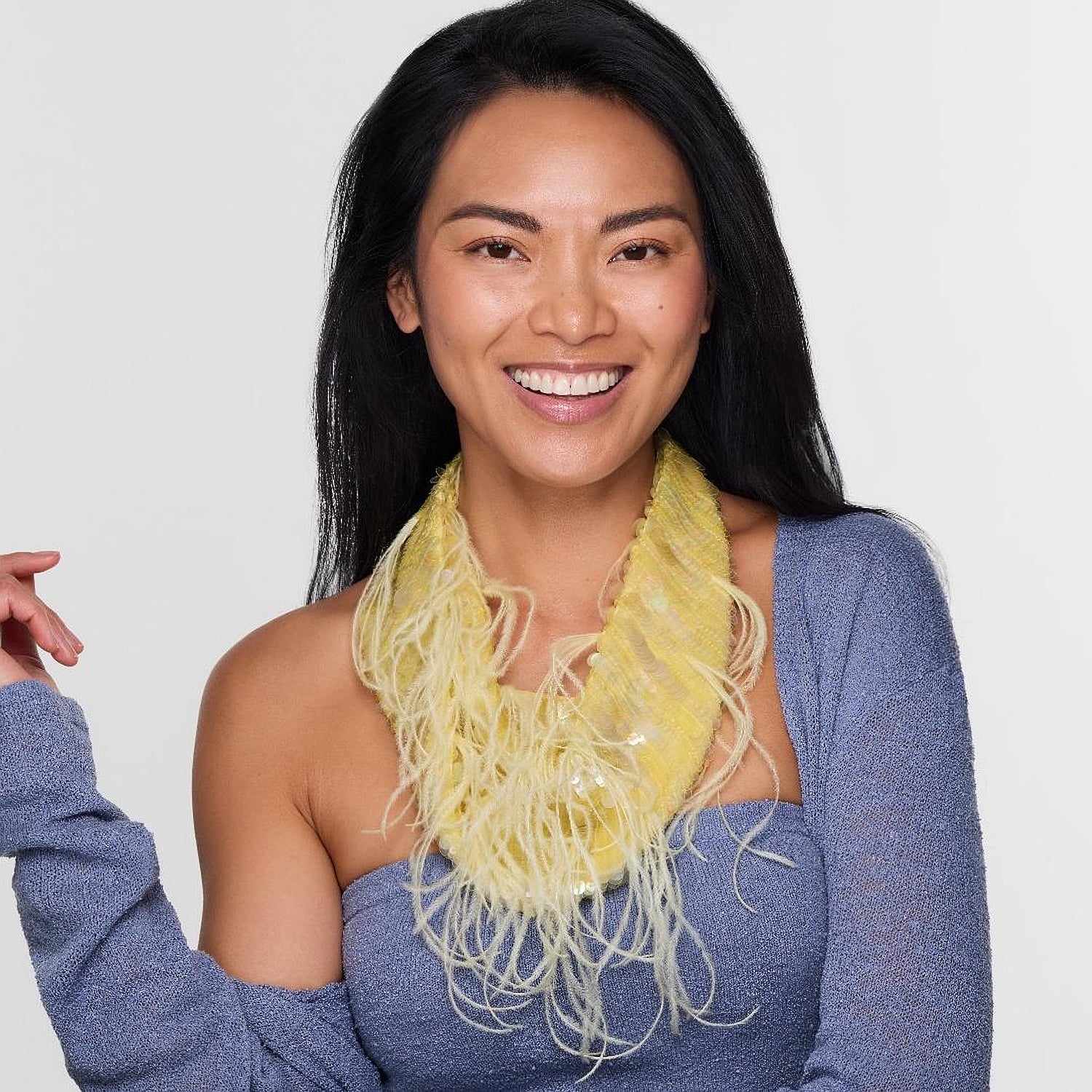 Woman wearing a blue top and yellow scarf against a white background