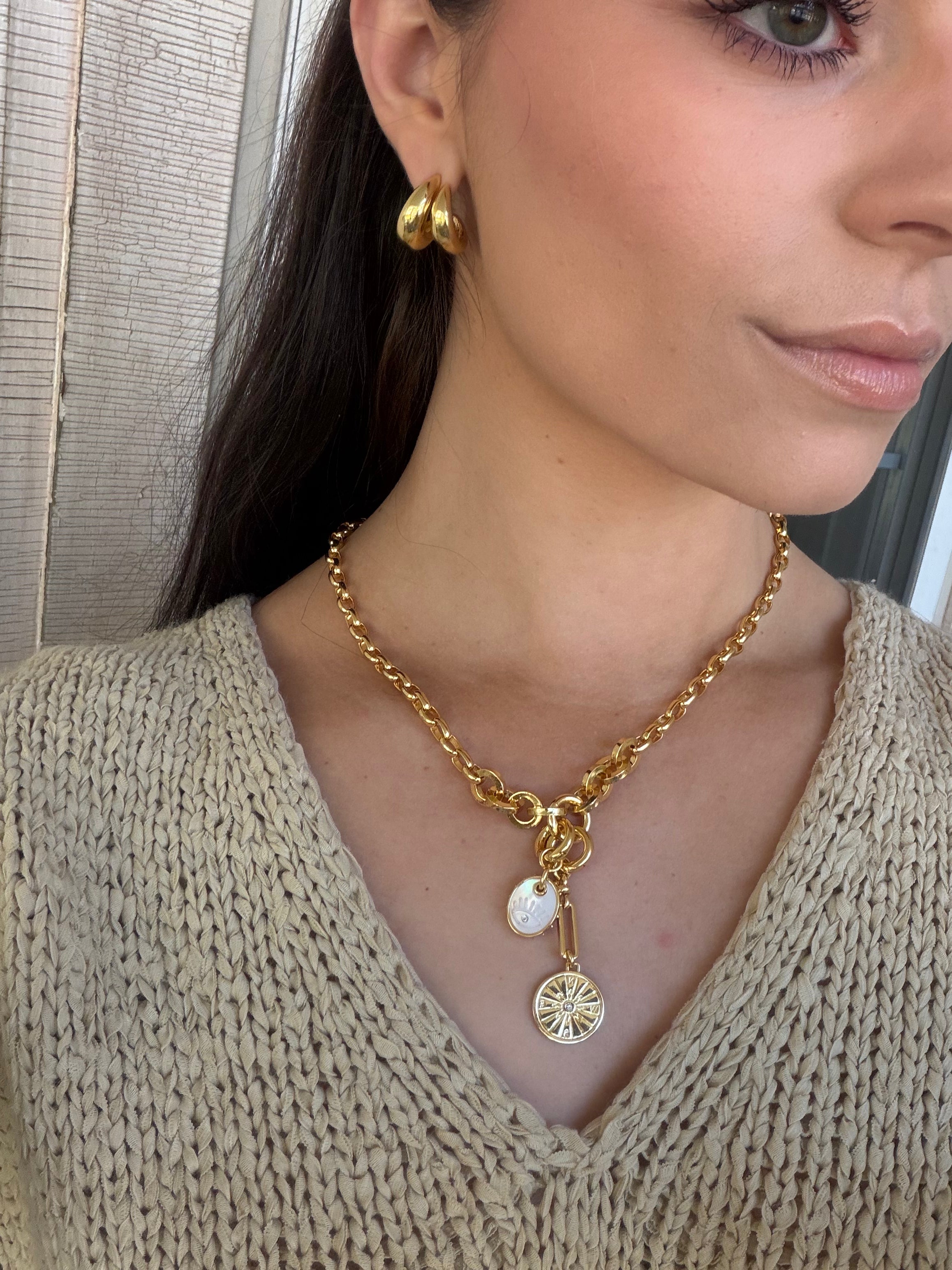 Woman wearing a gold necklace with pendant, close-up of neck and chest area.