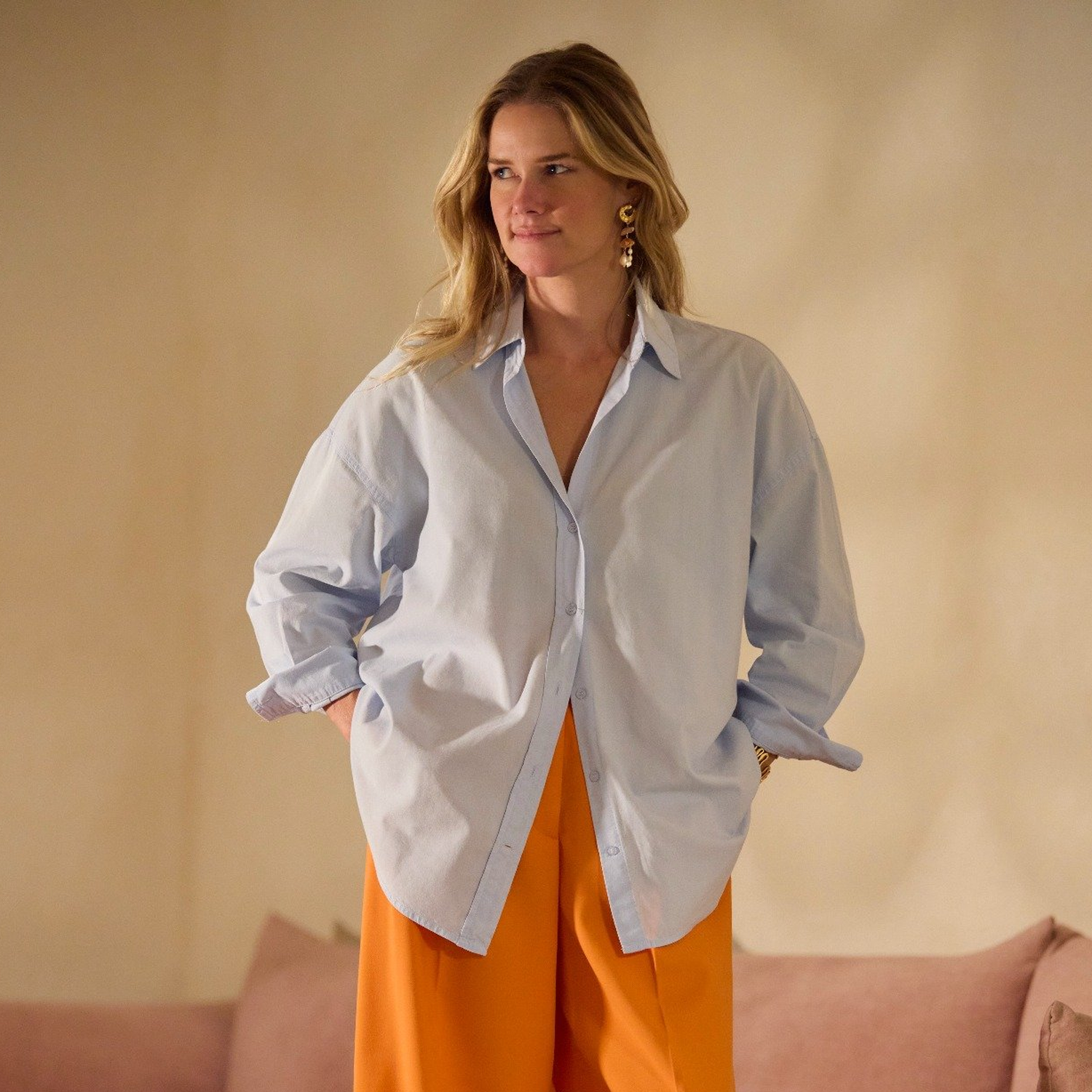 Model wearing gold and pearl drop earrings