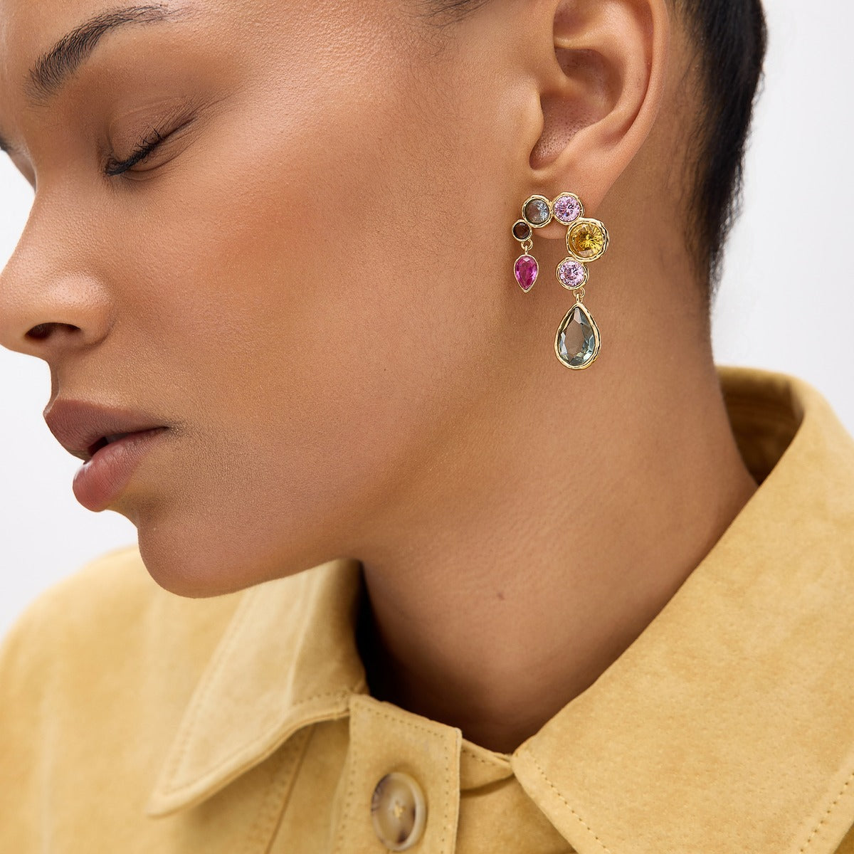 Close-up of a woman wearing colorful gemstone earrings with a blurred background
