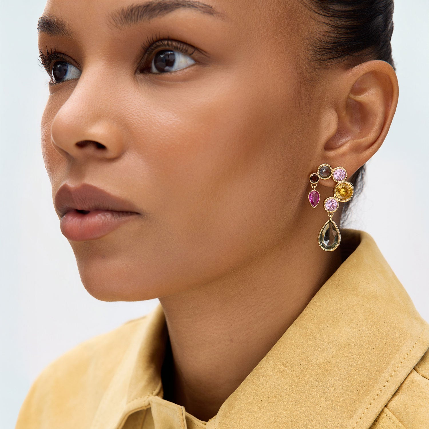 Close-up of a woman wearing colorful gemstone earrings with a blurred background