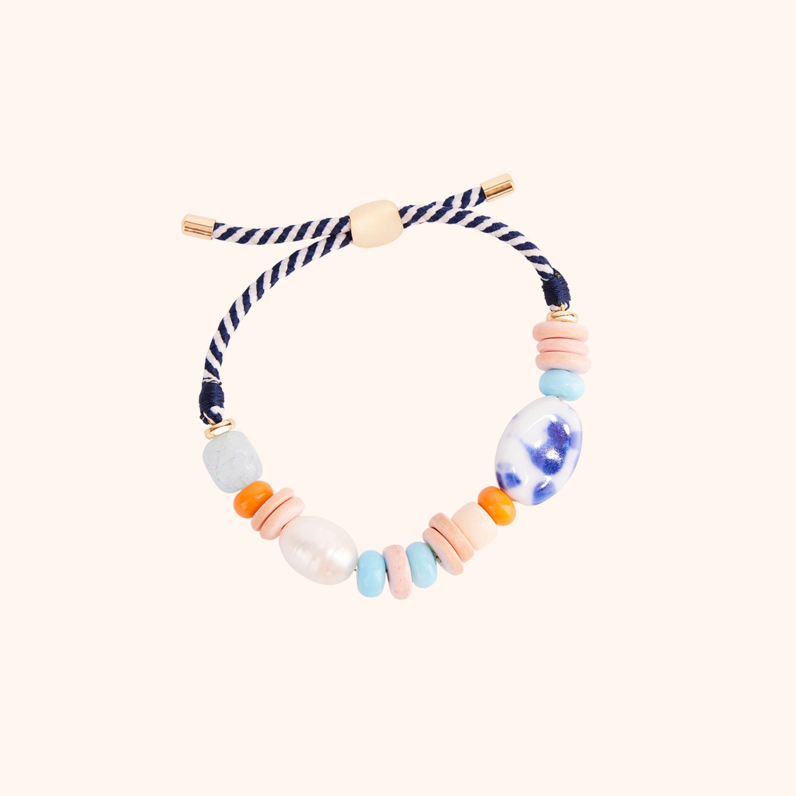 Orange and Blue Multi Bead and Pearl Bracelet on Flat Tan Background
