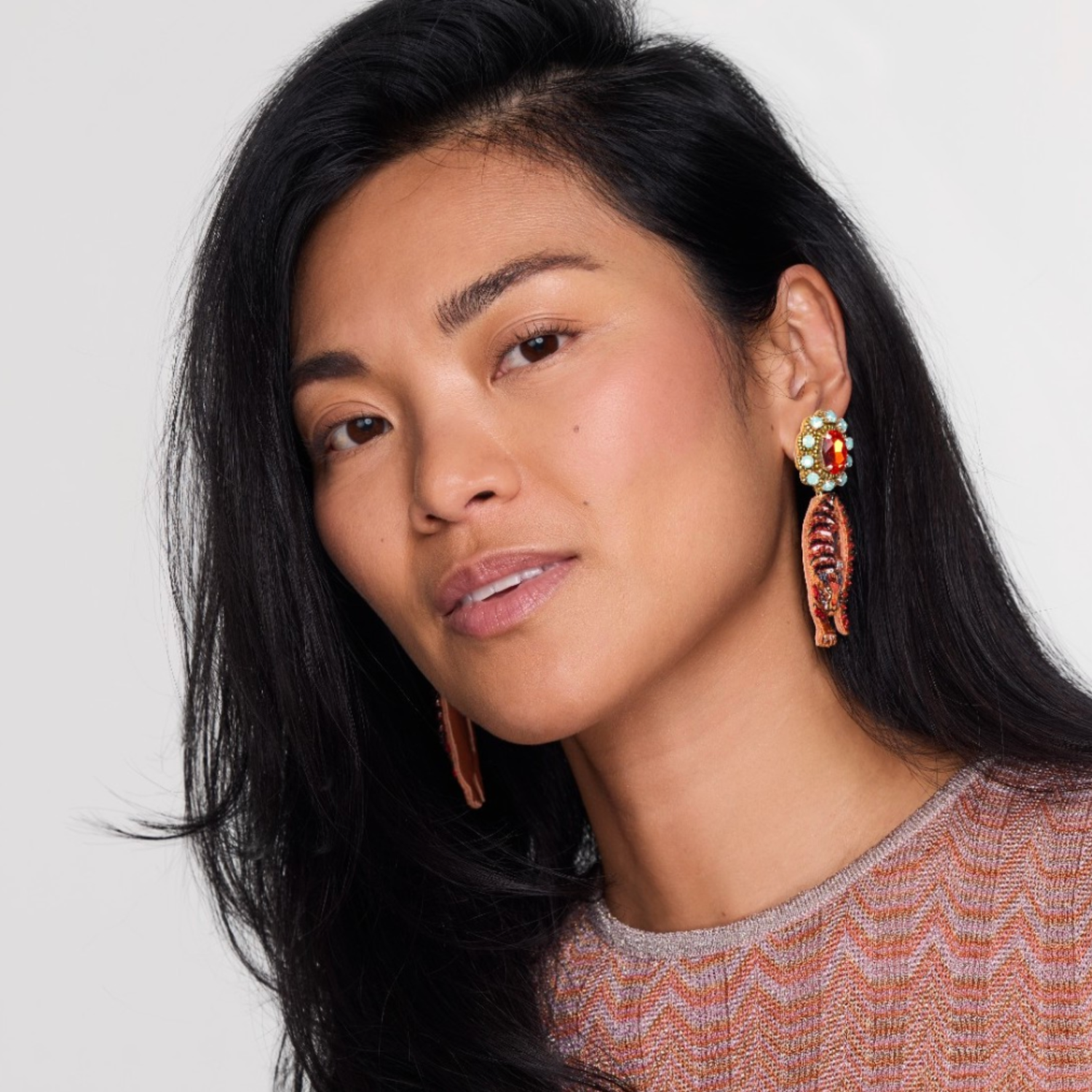 Woman wearing colorful earrings against a plain background