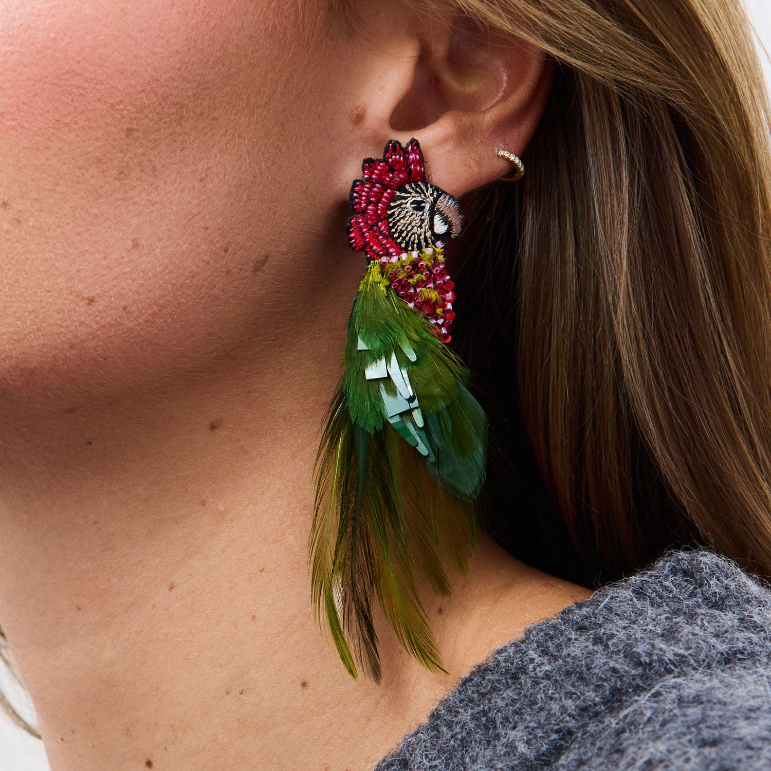 Close-up of a person wearing a colorful feathered bird earring.