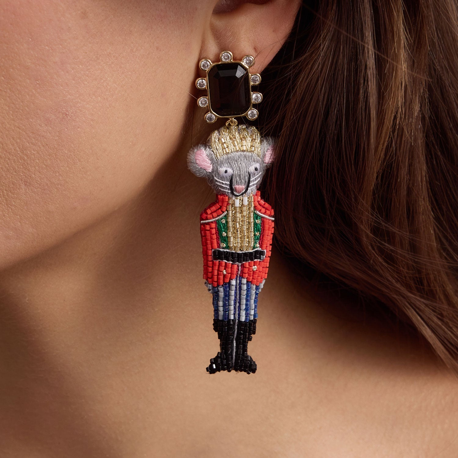 Earring shaped like a toy soldier with a prominent gemstone on an earlobe.