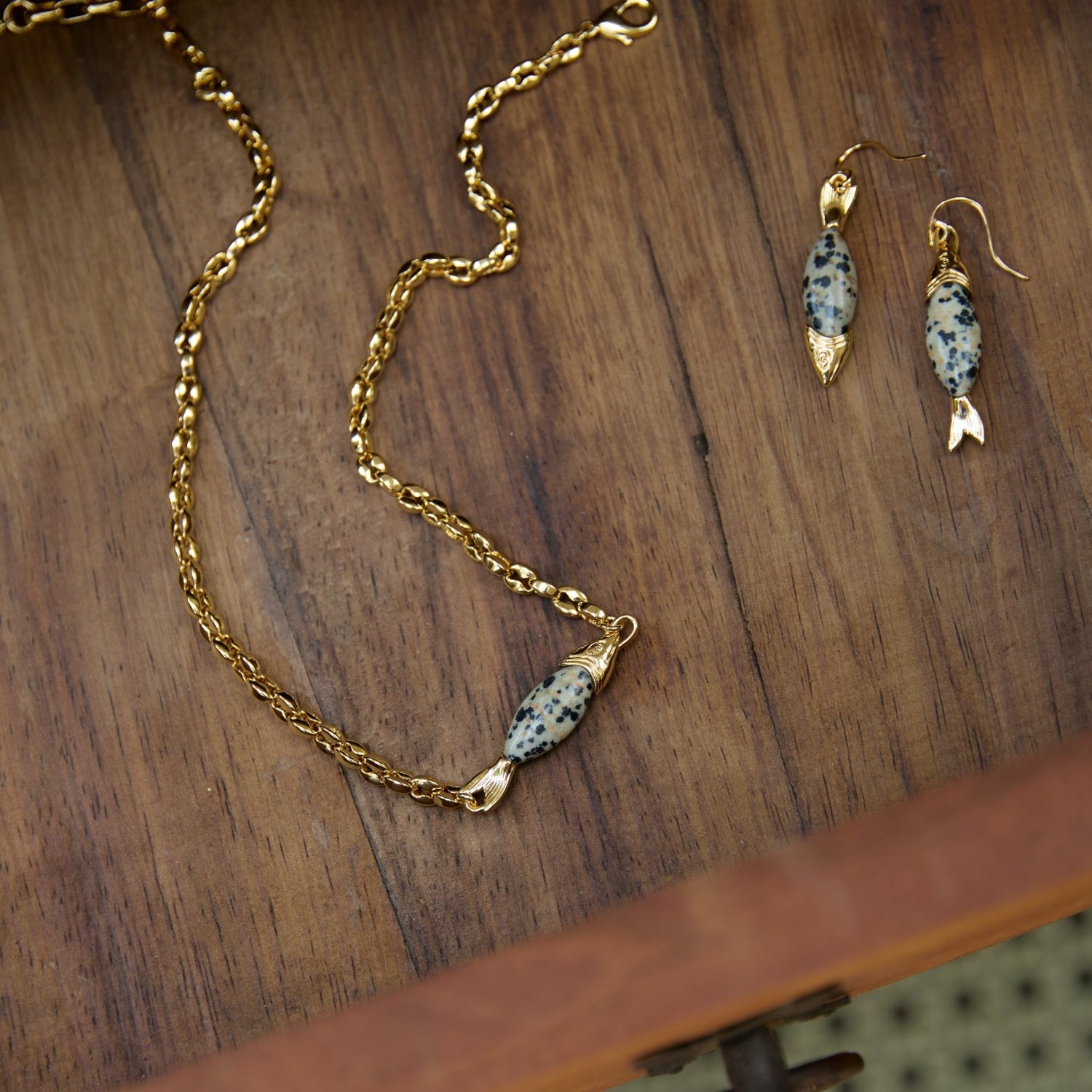 Gold necklace and earrings on a wooden surface
