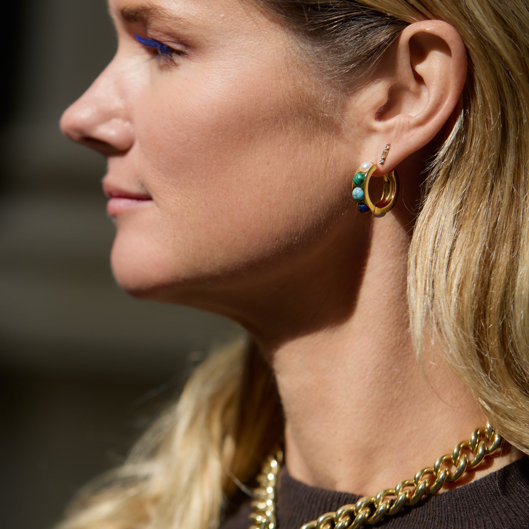 Maggie wearing stone and gold hoop earrings with blurred background