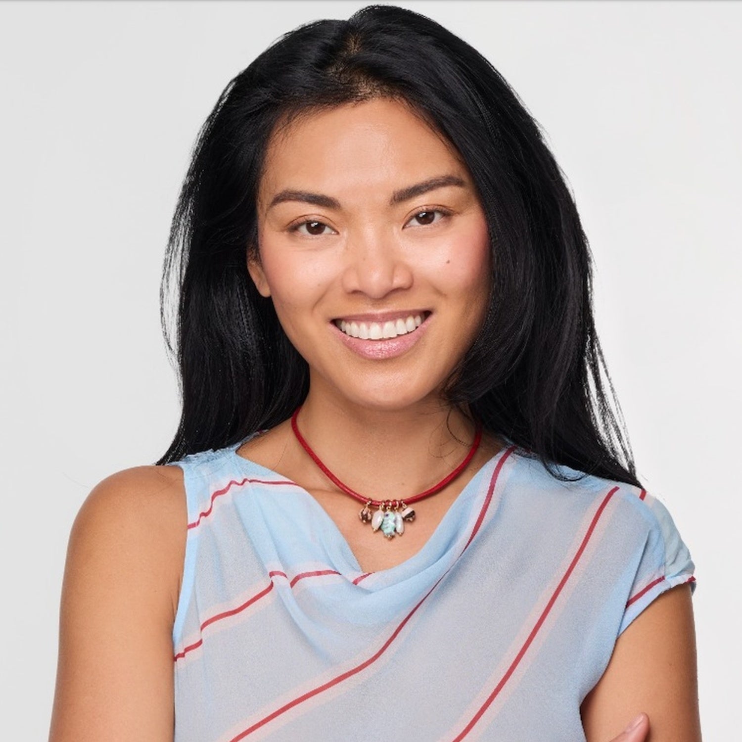 Woman wearing a light blue top with red stripes against a plain background