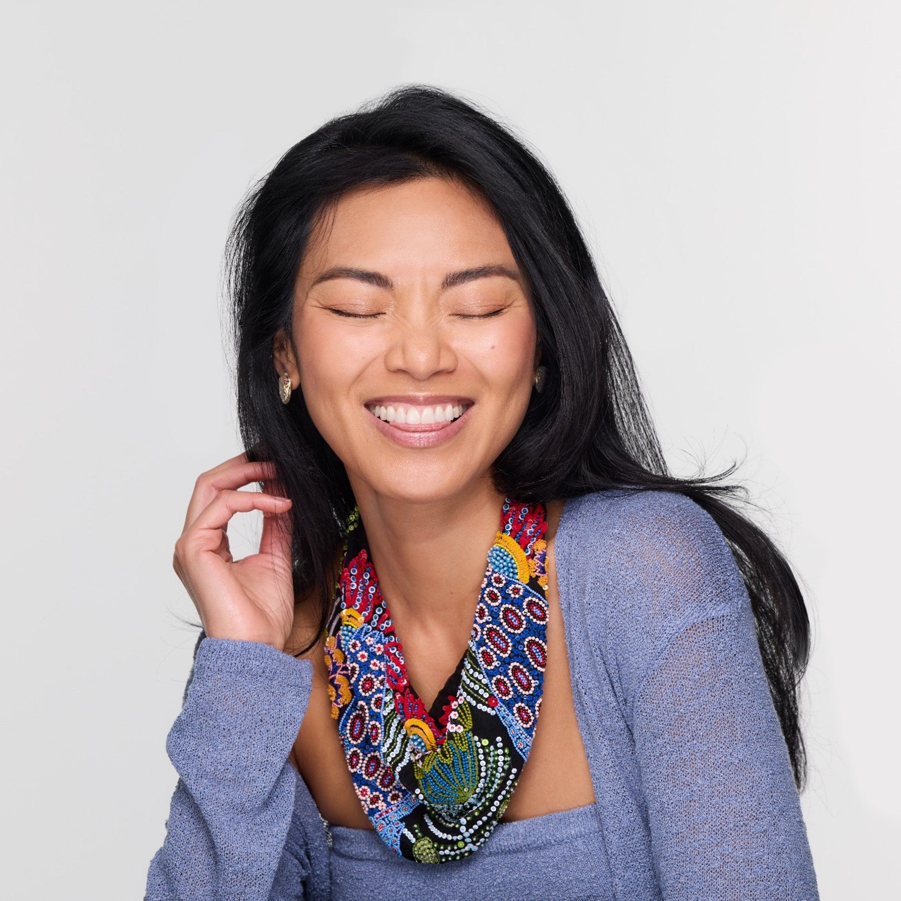 Woman wearing a colorful beaded necklace against a plain background