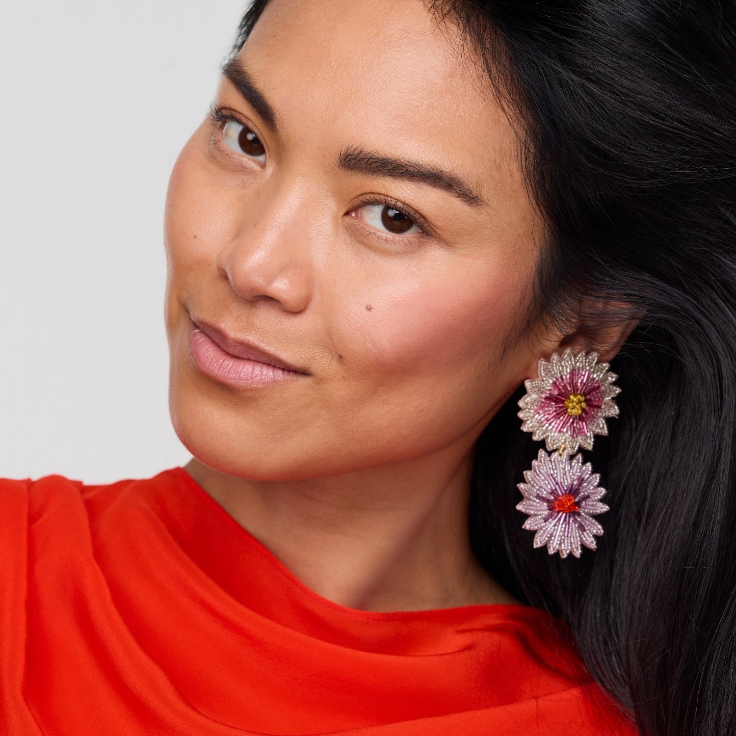 Woman wearing floral earrings with a plain background