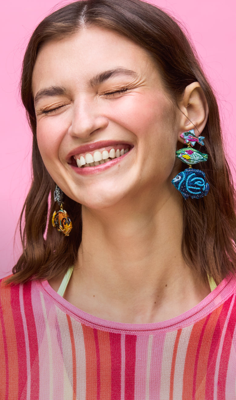 Woman wearing colorful earrings against a pink background