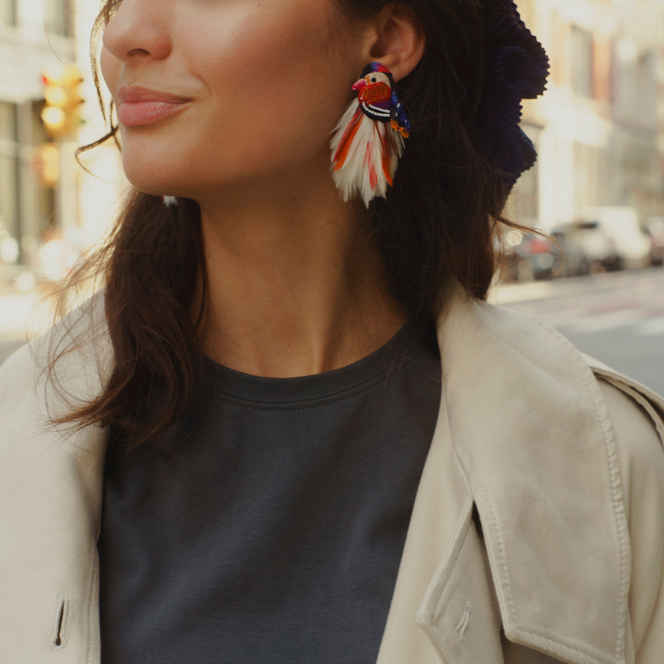 model styled as 20 year old wearing feather bird earrings and a neutral outfit