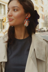 model styled as 20 year old wearing feather bird earrings and a neutral outfit