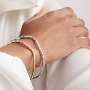 mixed metals shown side by side on a model wrist wearing a silver and a gold bangle bracelet