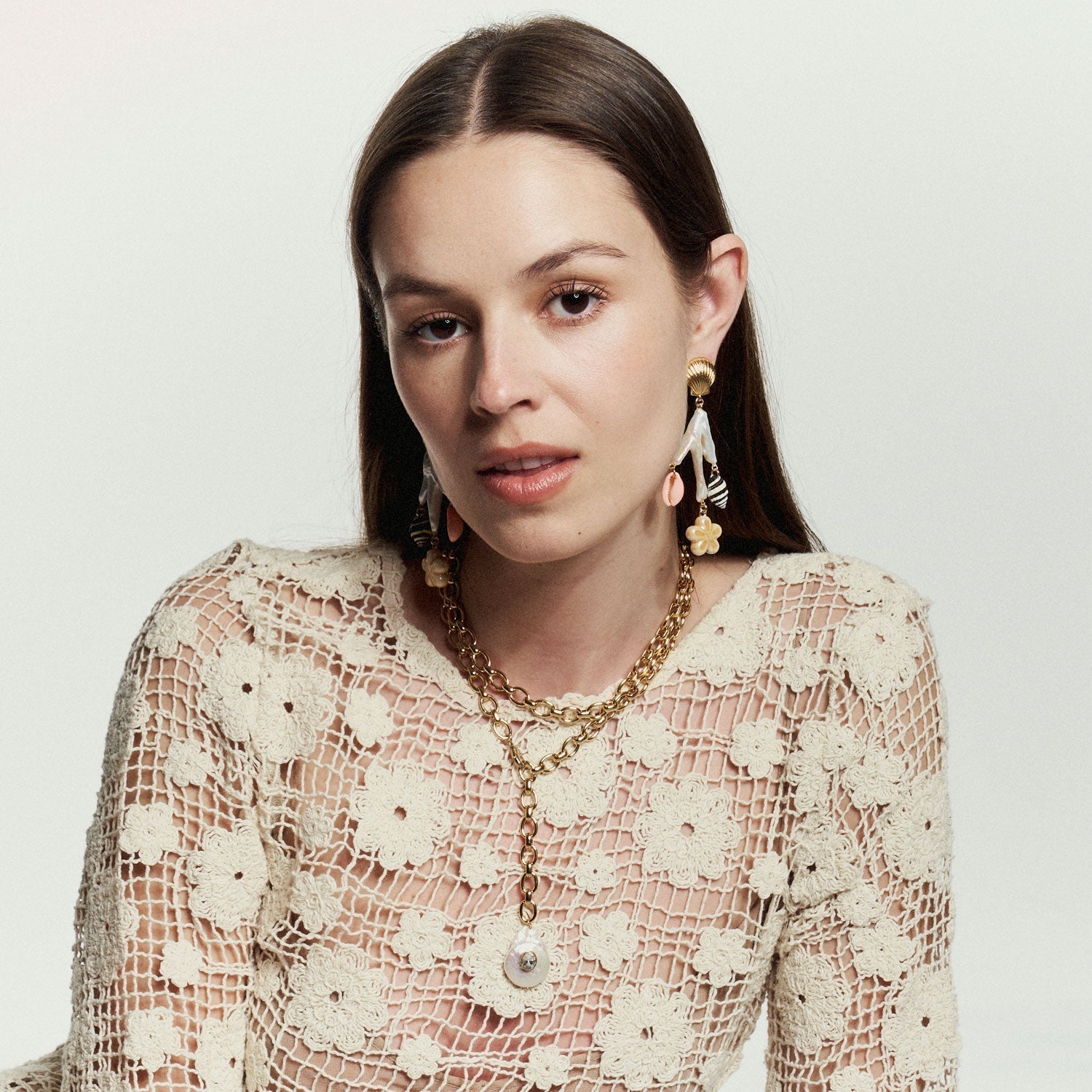 gold seashell drop earrings with beach themed gems and a gold link necklace on a woman