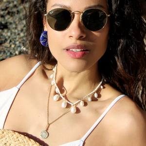 model wearing charm necklaces earrings and sunglasses shown up close in natural light