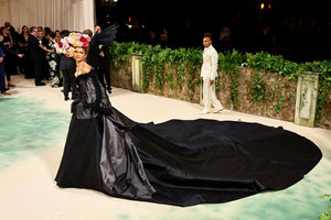 Zendaya wearing a black gown and floral fascinator posing at the Met Gala 2024