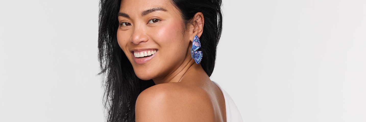 Model wearing butterfly embroidered earrings against white background