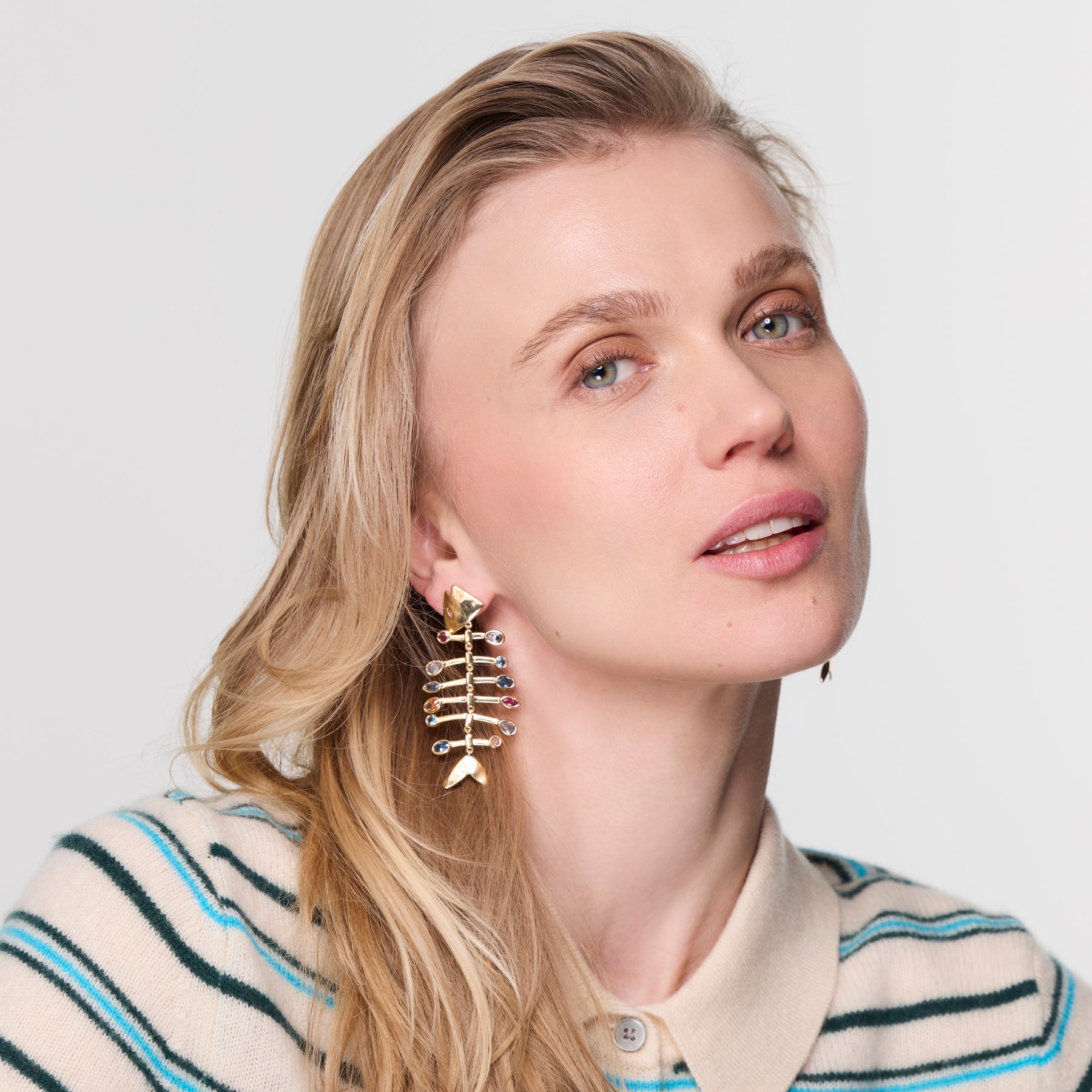 Woman wearing fishbone earrings with a neutral background