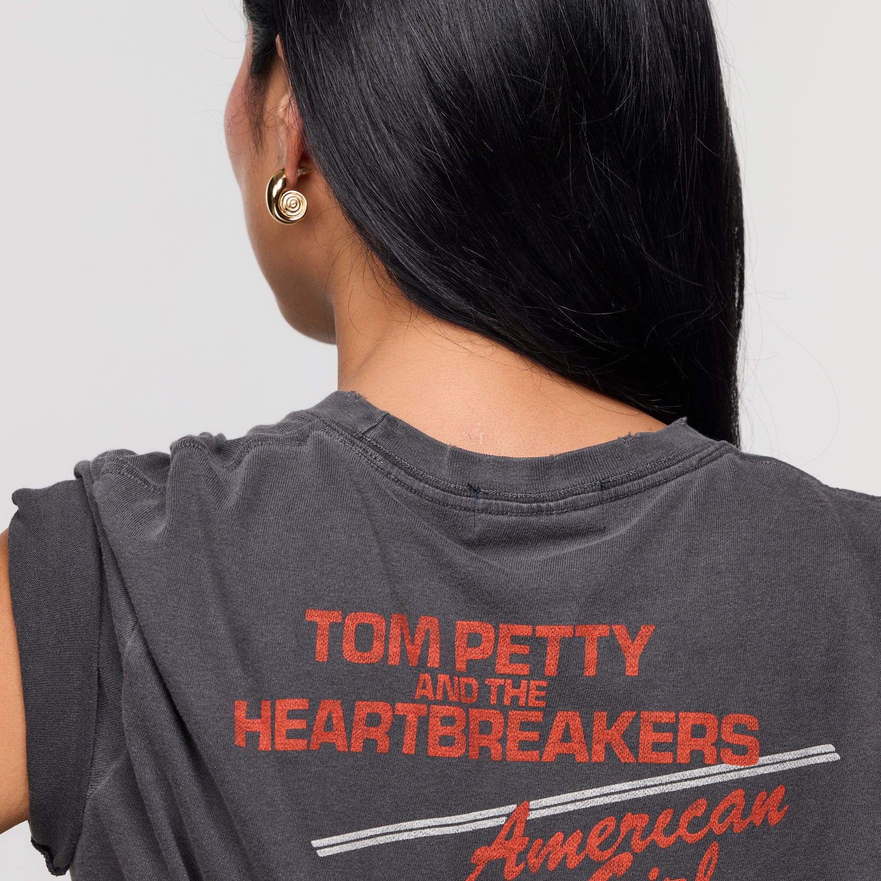 Model wearing gold spiral hoop earrings with t shirt on white background