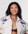 Woman wearing a colorful pink and blue shell necklace against a white background
