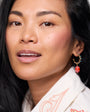Close-up of a woman wearing earrings with a neutral background