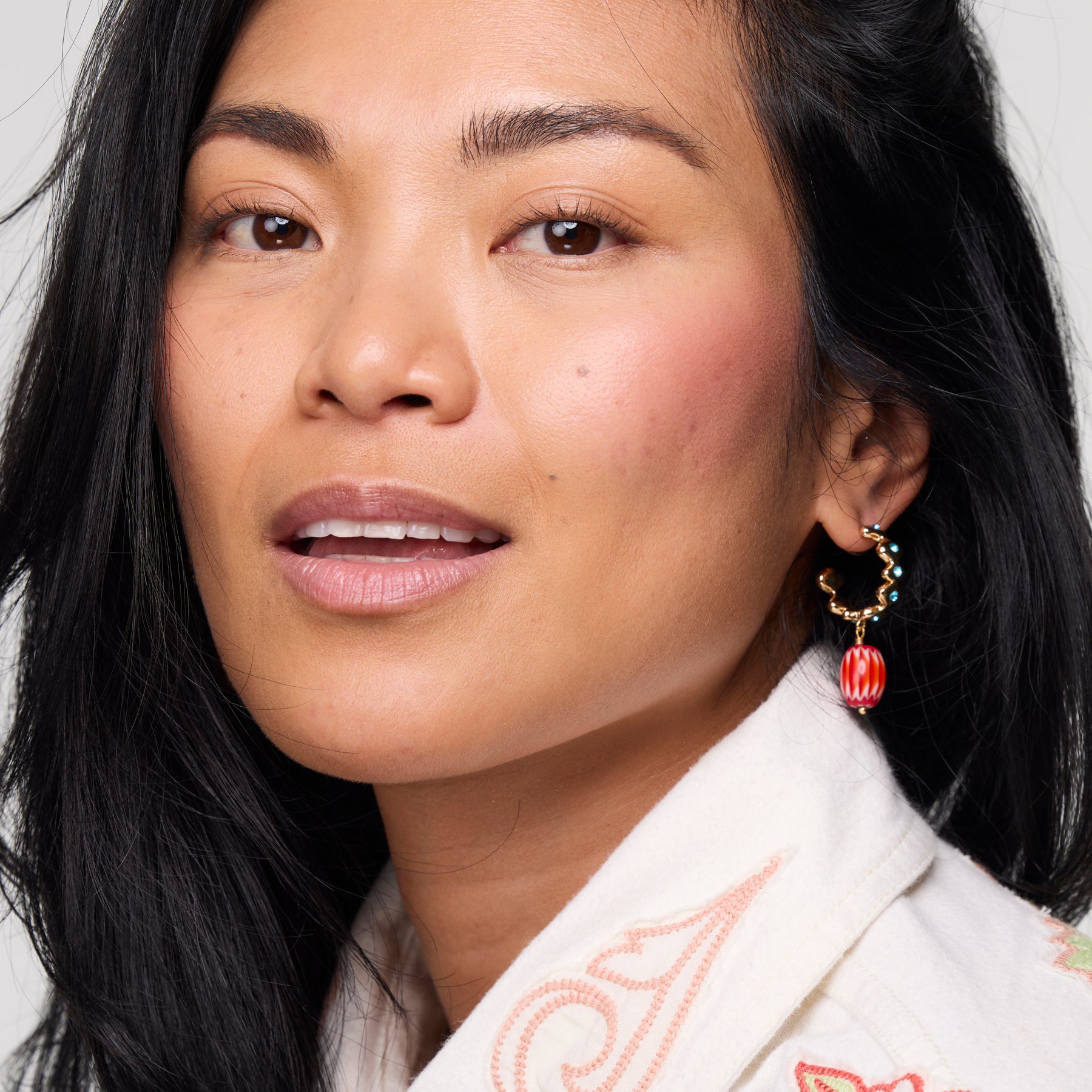 Close-up of a woman wearing earrings with a neutral background